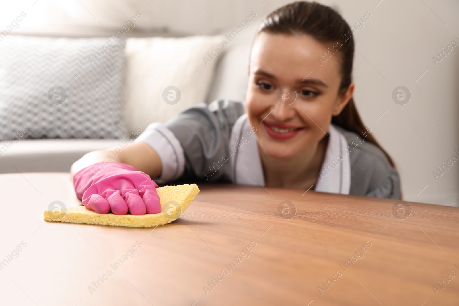 Photo of Young chambermaid wiping dust from table in hotel room, closeup. Space for text