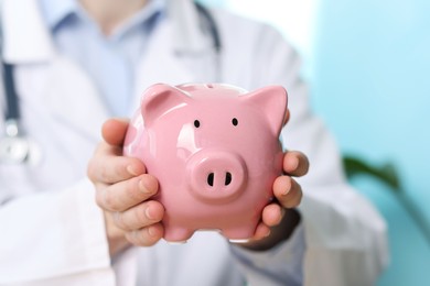 Photo of Doctor with piggy bank in hospital, closeup