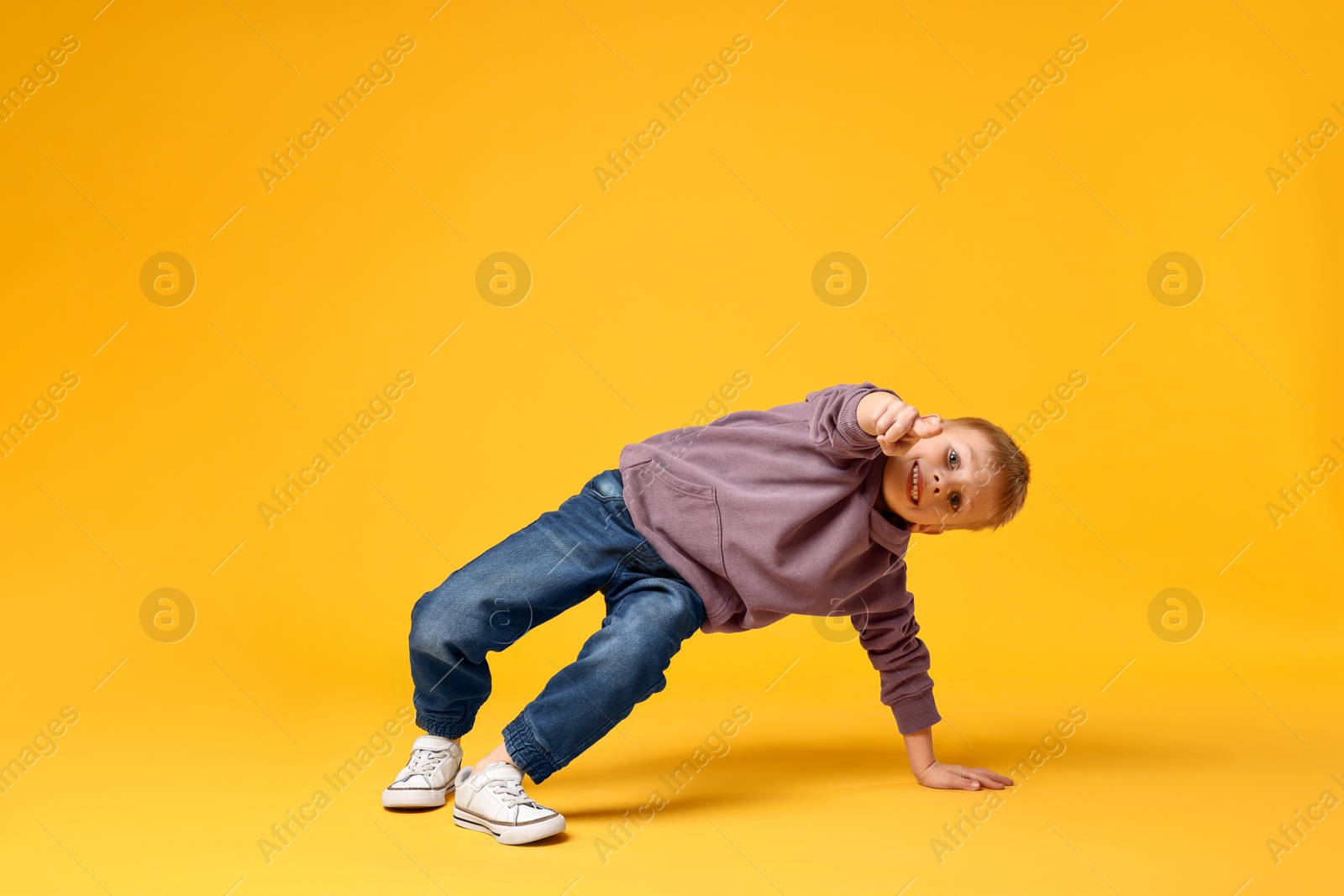 Photo of Happy little boy dancing on yellow background