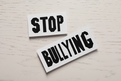 Photo of Paper cards with text Stop Bullying on white wooden table, flat lay
