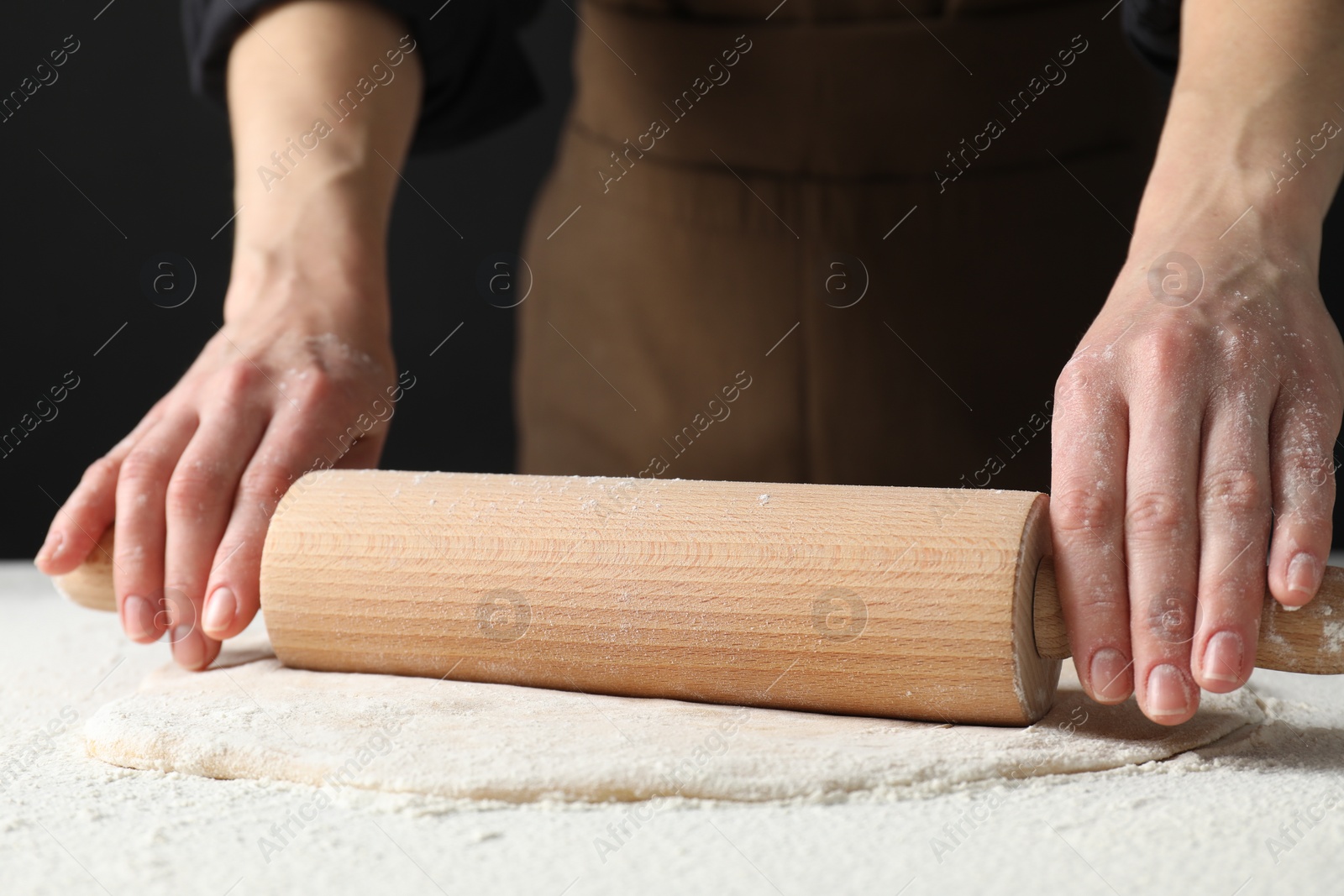 Photo of Woman rolling raw dough at table, closeup