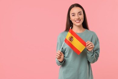 Photo of Young woman holding flag of Spain on pink background, space for text