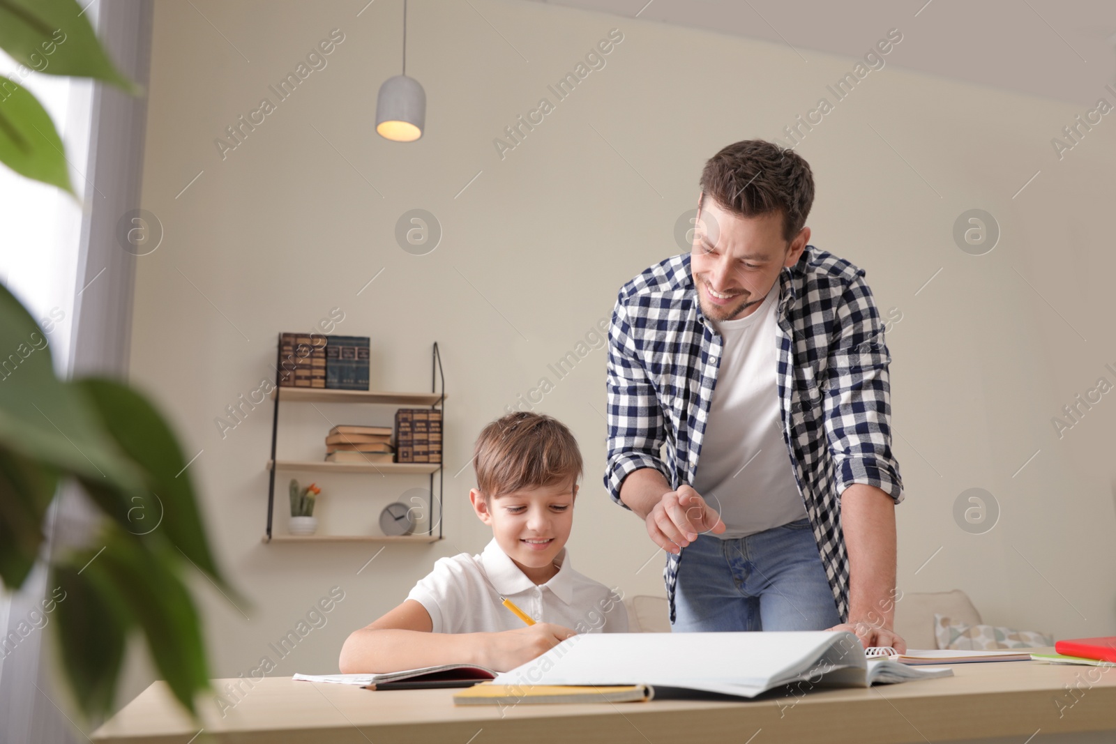 Photo of Dad helping his son with school assignment at home