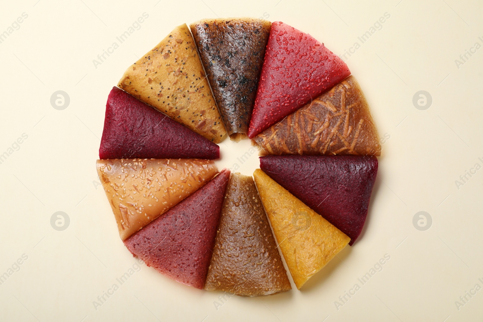 Photo of Delicious fruit leather rolls on beige background, flat lay