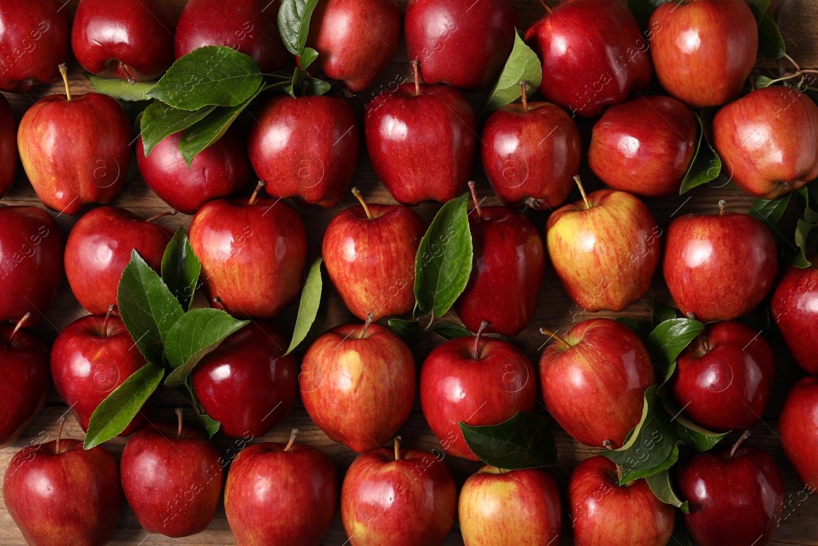 Photo of Fresh ripe apples with leaves on wooden table, flat lay