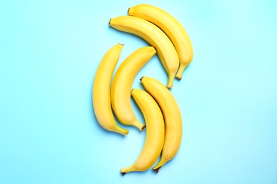 Ripe tasty bananas on blue background, flat lay