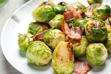 Photo of Delicious Brussels sprouts with bacon on plate, closeup