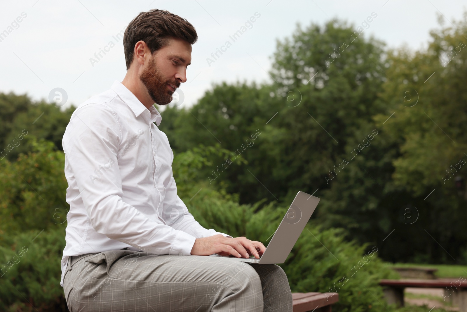 Photo of Handsome businessman with laptop on bench in park