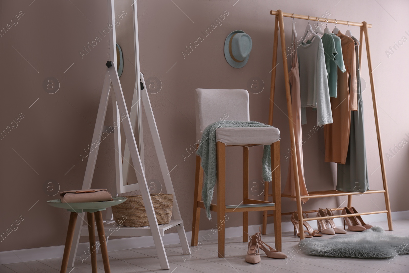 Photo of Modern dressing room interior with clothing rack, stool and mirror