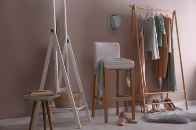 Modern dressing room interior with clothing rack, stool and mirror