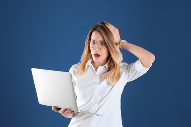 Photo of Portrait of shocked young woman in office wear with laptop on color background