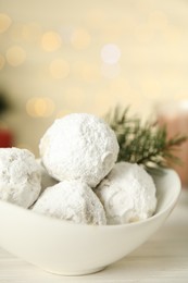 Photo of Bowl with tasty Christmas snowball cookies on wooden table, closeup