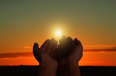 Image of Muslim woman praying outdoors at sunset, closeup