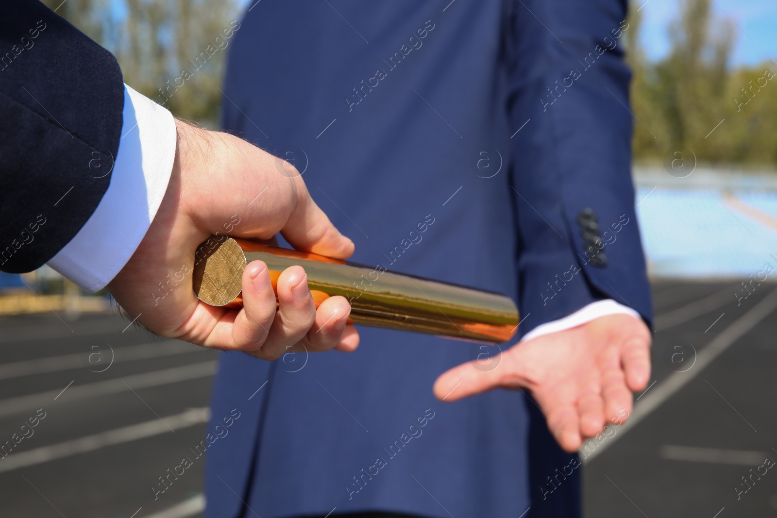 Photo of Businessman passing baton to his partner outdoors, closeup