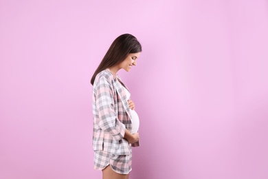 Happy pregnant woman posing on color background