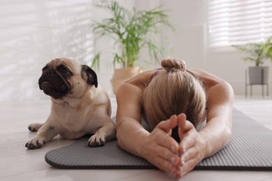 Photo of Woman with dog practicing yoga at home