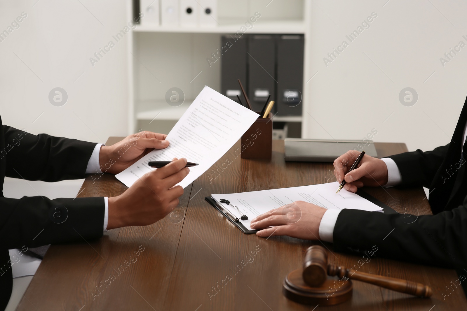 Photo of Law and justice. Lawyers working with documents at wooden table in office, closeup