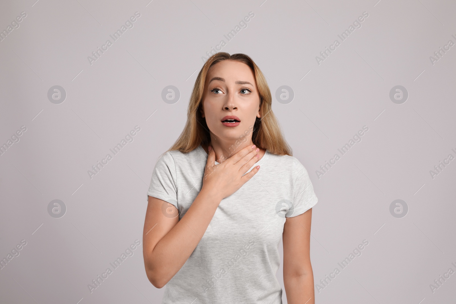 Photo of Young woman suffering from pain during breathing on light grey background