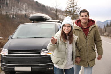 Happy couple near car on road. Winter vacation