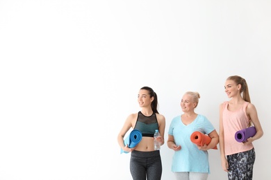 Photo of Women in sportswear with yoga mats on white background