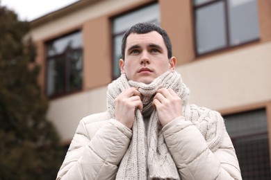 Sick young man in warm clothes on city street