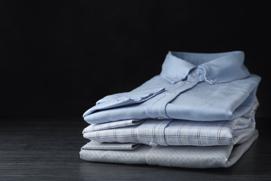 Photo of Stack of classic shirts on black wooden table