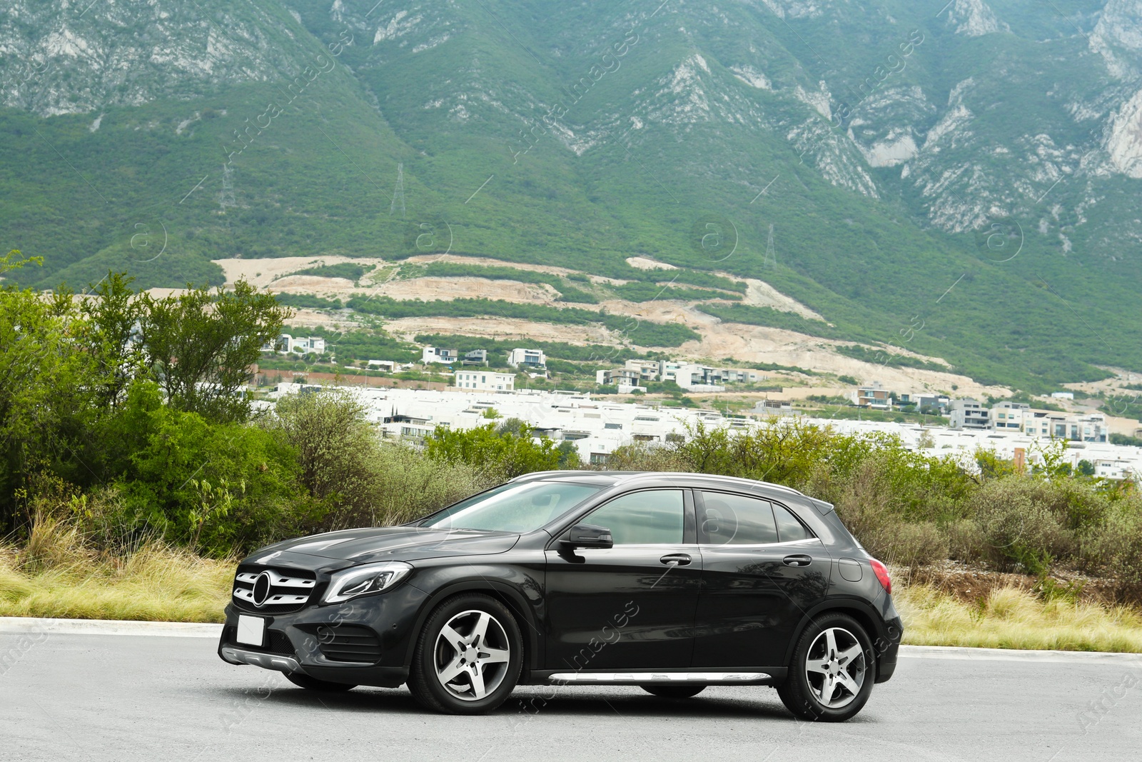 Photo of Beautiful modern black car on road near mountains