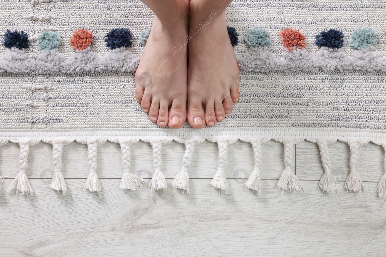 Photo of Woman standing on carpet with pattern at home, top view