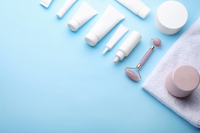 Photo of Natural face roller, cosmetic products and towel on light blue background, above view. Space for text