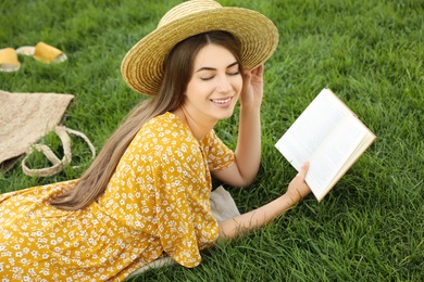 Photo of Young woman reading book on green grass