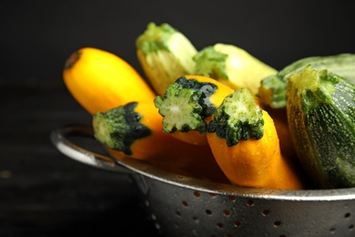 Photo of Colander with fresh ripe zucchini on dark background, closeup