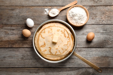 Photo of Flat lay composition with thin pancakes and ingredients on wooden background