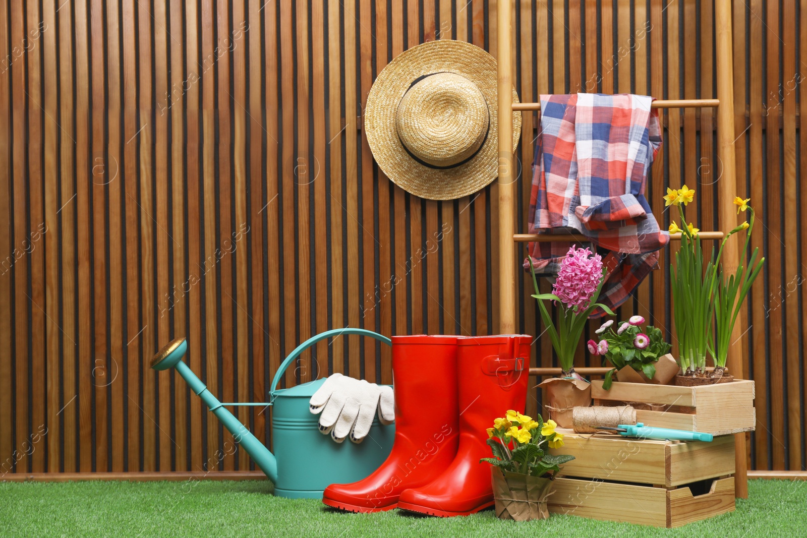 Photo of Composition with different gardening tools on artificial grass at wooden wall. Space for text