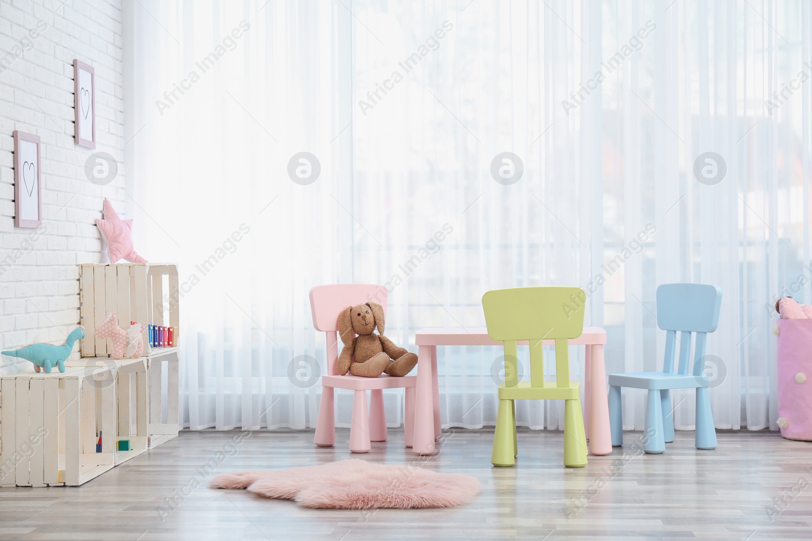 Photo of Cozy kids room interior with table, chairs and toys