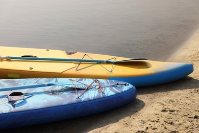 Photo of SUP boards with paddles on river shore