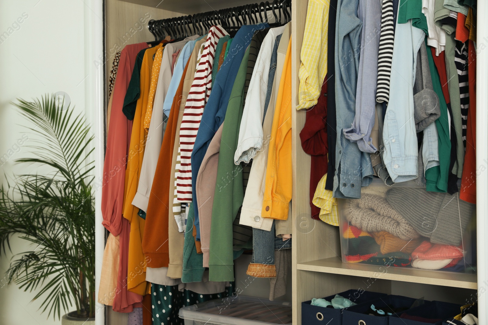 Photo of Wardrobe closet with different stylish clothes and home stuff in room. Fast fashion