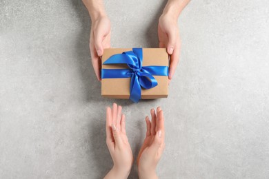 Photo of Man giving gift box to woman on light gray background, top view