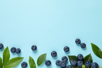 Photo of Tasty fresh blueberries with green leaves on light blue background, flat lay. Space for text