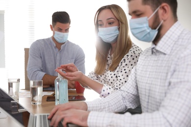 Photo of Group of coworkers with protective masks in office. Business meeting during COVID-19 pandemic