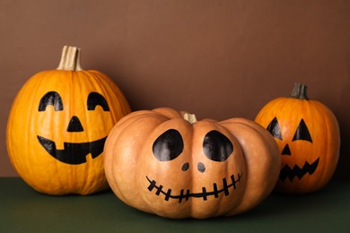 Photo of Pumpkins with drawn spooky faces on color background. Halloween celebration