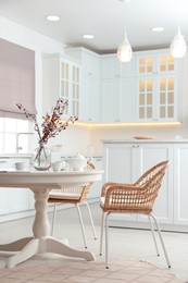 Photo of Dining room interior with tea set on round table and wicker chairs