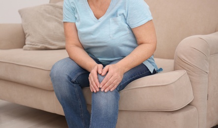 Senior woman suffering from knee pain at home, closeup