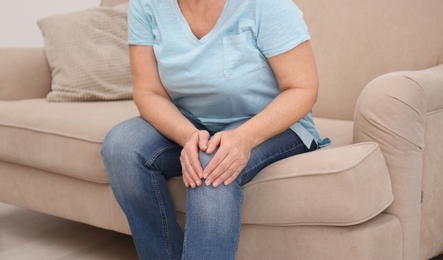 Photo of Senior woman suffering from knee pain at home, closeup