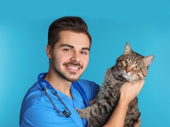 Photo of Veterinarian doc with cat on color background
