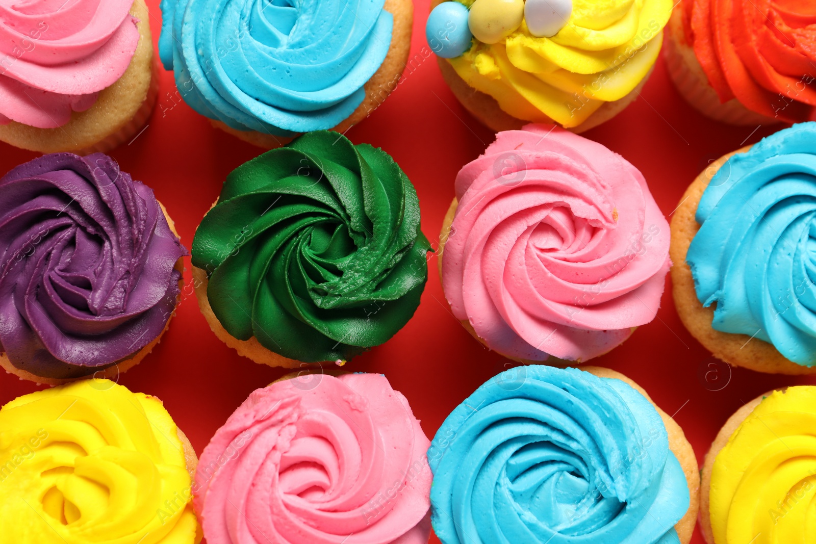 Photo of Delicious cupcakes with bright cream on red background, flat lay