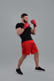 Man in boxing gloves on grey background