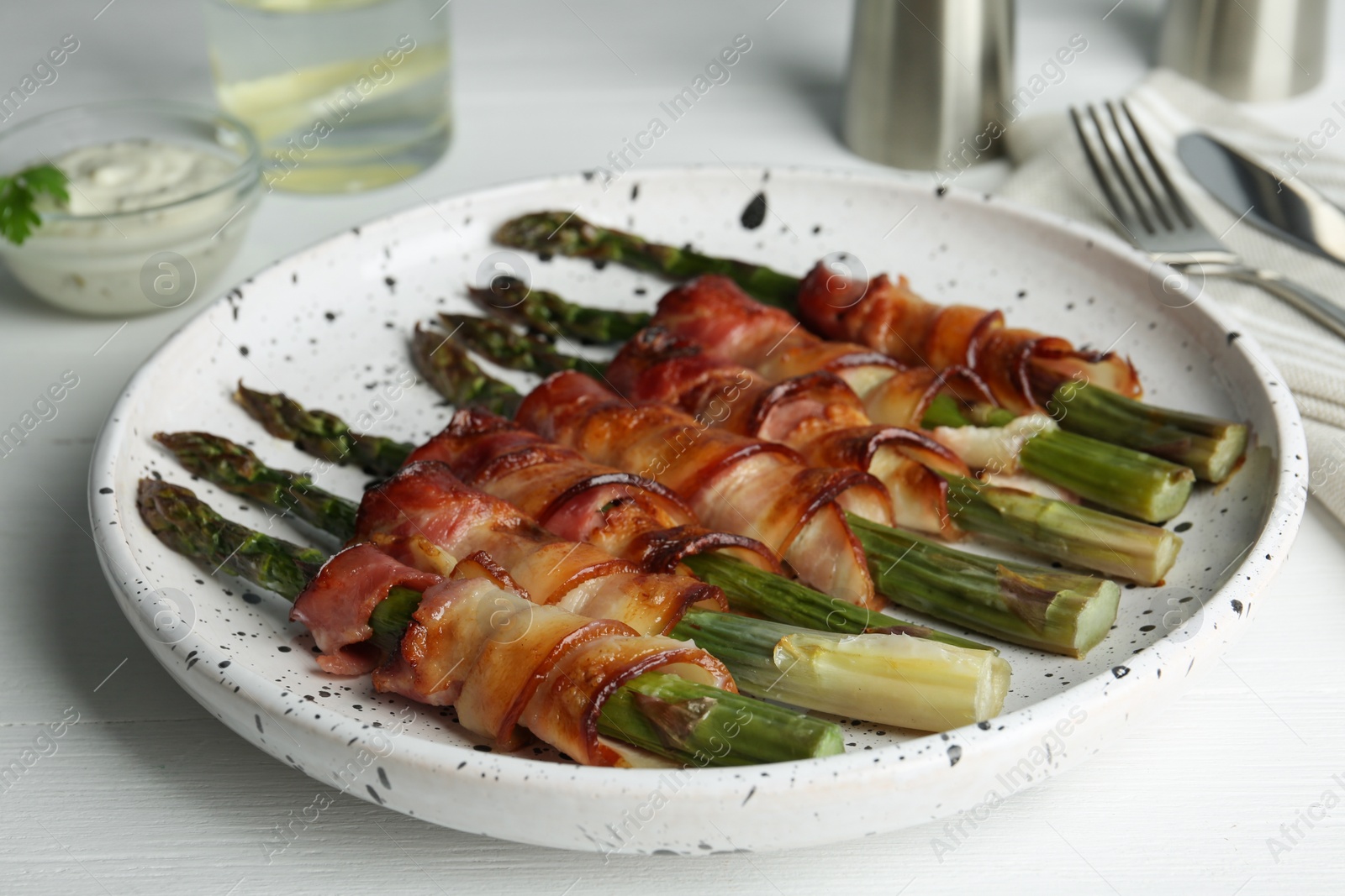 Photo of Oven baked asparagus wrapped with bacon on white table, closeup