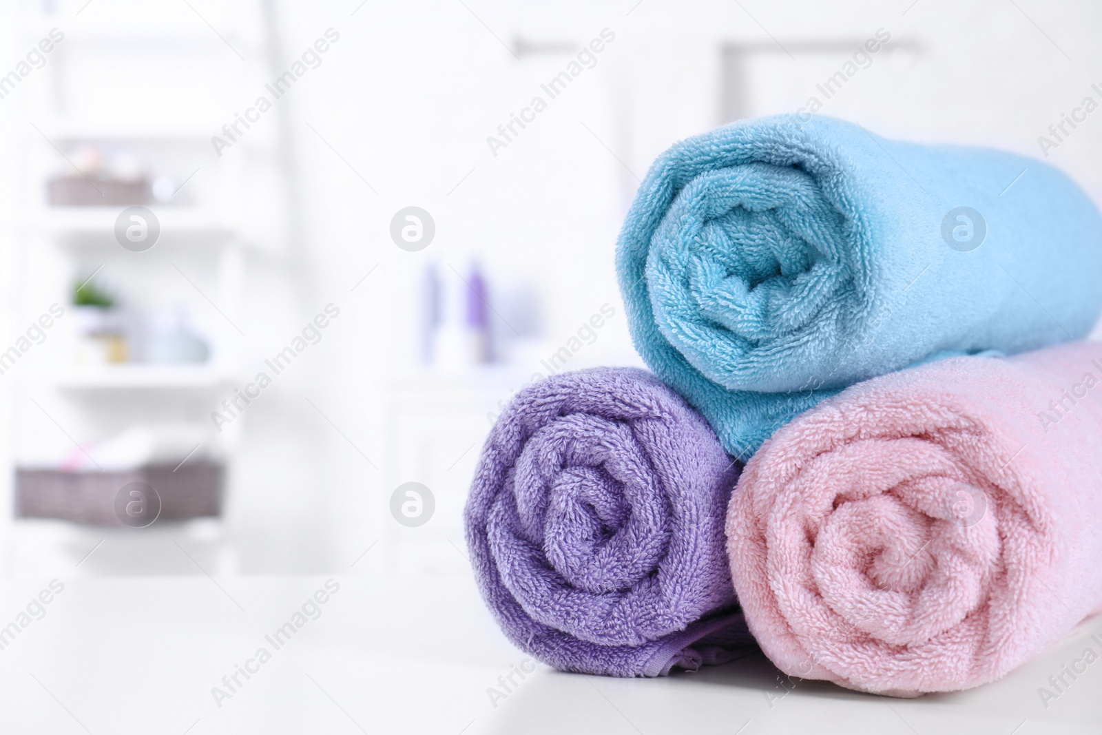 Photo of Rolled tidy towels on table in bathroom. Space for text