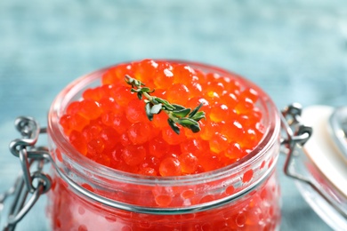 Glass jar with delicious red caviar on table, closeup