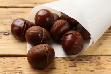 Fresh edible sweet chestnuts on wooden table, closeup